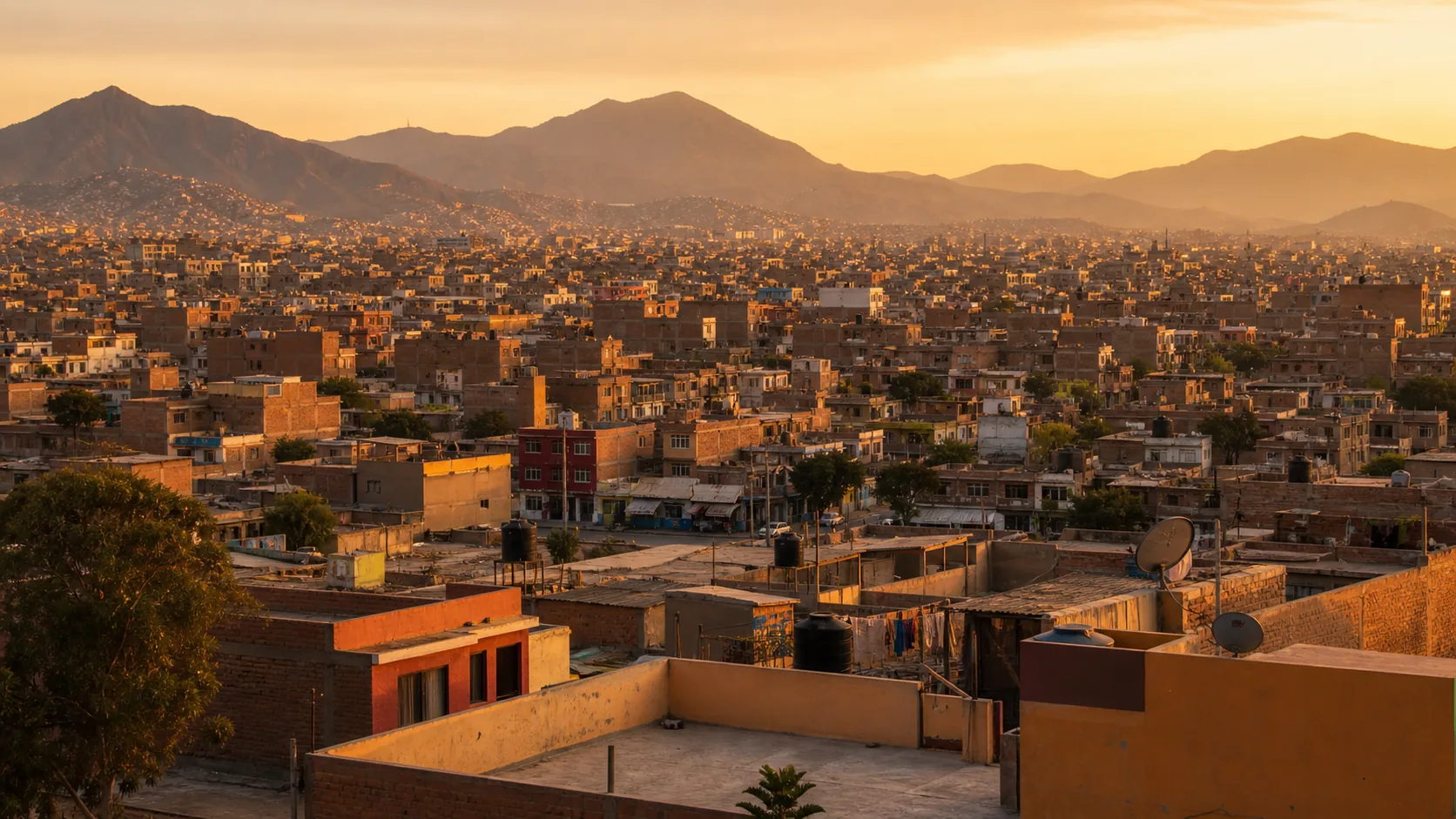 Vista panorámica de un distrito residencial de Lima Norte al atardecer, con rooftops de casas bajas y los Andes al fondo.